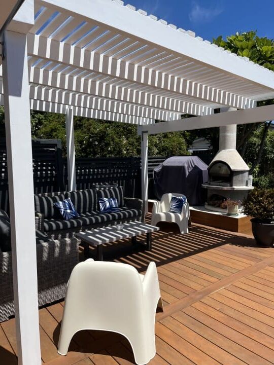 Pergola provides shading for outdoor living with pizza oven area and revived timber decking by SWT building